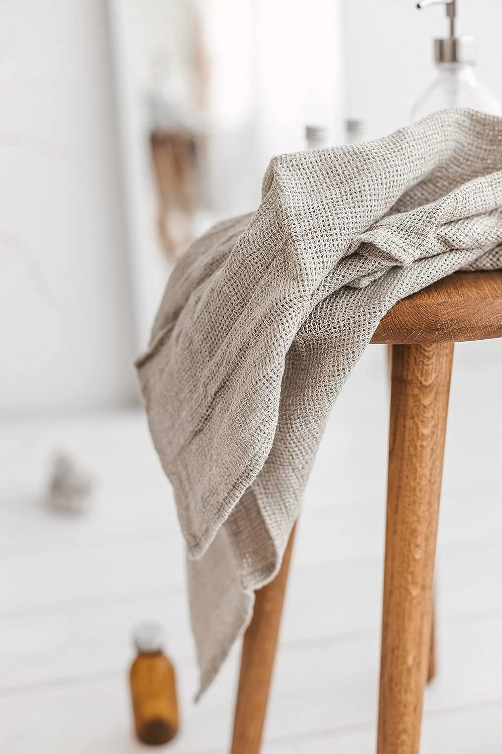 Natural woven linen draped over a wooden stool in a bright interior