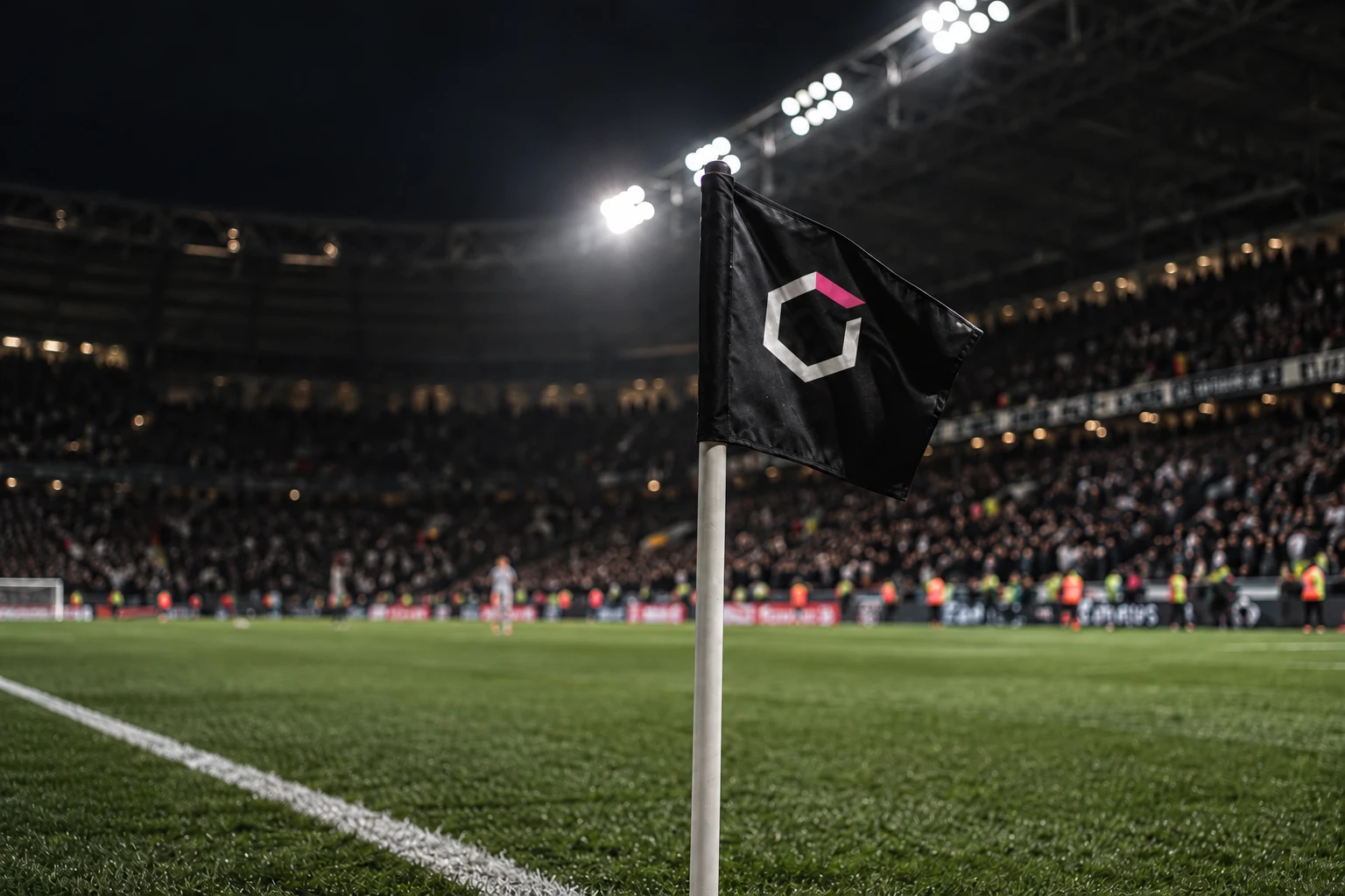 A black Unboxed corner flag in a floodlit football stadium at night